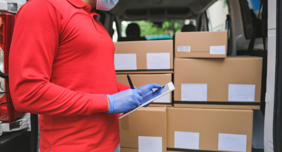 Delivery man checking with digital tablet the package while wearing surgical face mask for coronavirus - Work with new safety mesaures